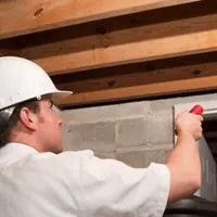 Termite inspection technician checking a basement wall and framing for termite activity in Little Rock, AR